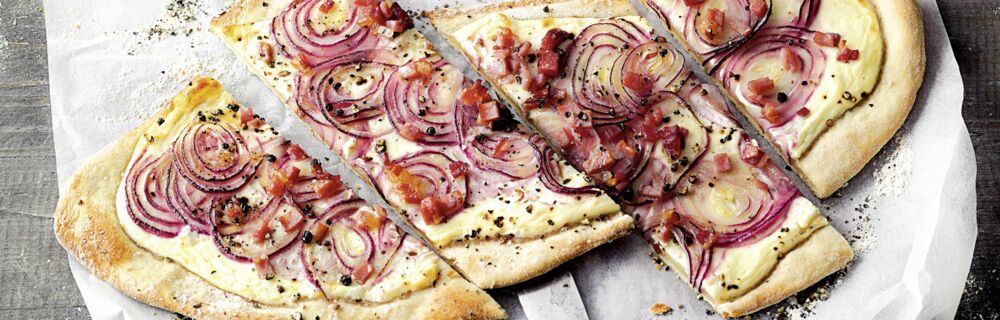 Zu den bekanntesten französischen Rezepten zählt der Elsässer Flammkuchen: Ein dünner Teig, bestrichen mit Crème fraîche und belegt mit Speck und Zwiebeln Französische Rezepte