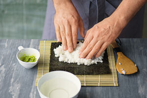 Sushi selber essen Hoso Maki Sushireis auf Noriblatt verteilen