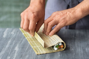 Sushi selber essen Hoso Maki Sushimatte über Sushirolle legen
