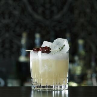 Glas mit Whisky Sour Mix, Eiswürfeln und drei Kirschen auf Holzspieß - Whisky Sour Rezept Whiskey Sour