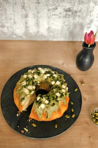 Guglhupf mit Topping aus Pistaziencreme, Pistazien und Stückchen weißer Schokolade. White-Chocolate-Kuchen mit Pistaziencreme