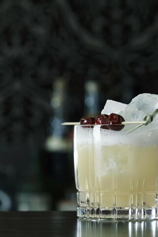 Glas mit Whisky Sour Mix, Eiswürfeln und drei Kirschen auf Holzspieß - Whisky Sour Rezept Whiskey Sour