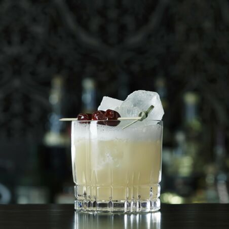 Glas mit Whisky Sour Mix, Eiswürfeln und drei Kirschen auf Holzspieß - Whisky Sour Rezept Whiskey Sour